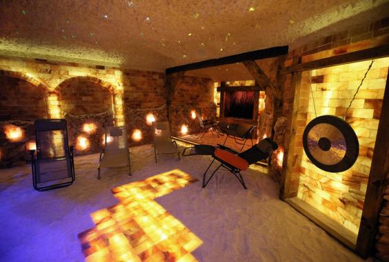 Entspannungsraum mit Salzsteinwänden und Boden, mehreren Liegestühlen und einem großen Gong an der Wand