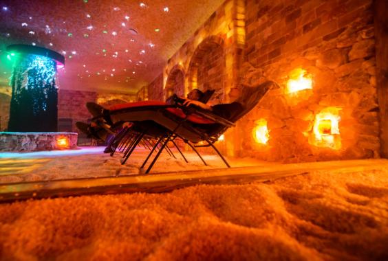 Entspannungsraum mit Liegestühlen, warmem Licht und Wänden aus Naturstein in einer Wellnessanlage