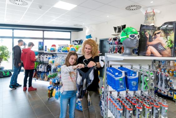 Zwei Frauen vergleichen Badeanzüge in einem Sportgeschäft mit Schwimmzubehör und Accessoires